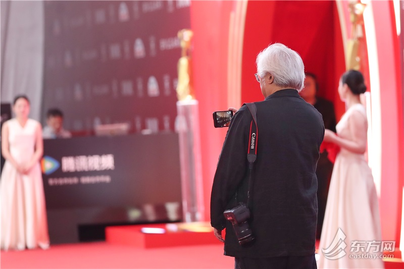 一名红毯嘉宾拿着相机记录颁奖之夜的精彩瞬间