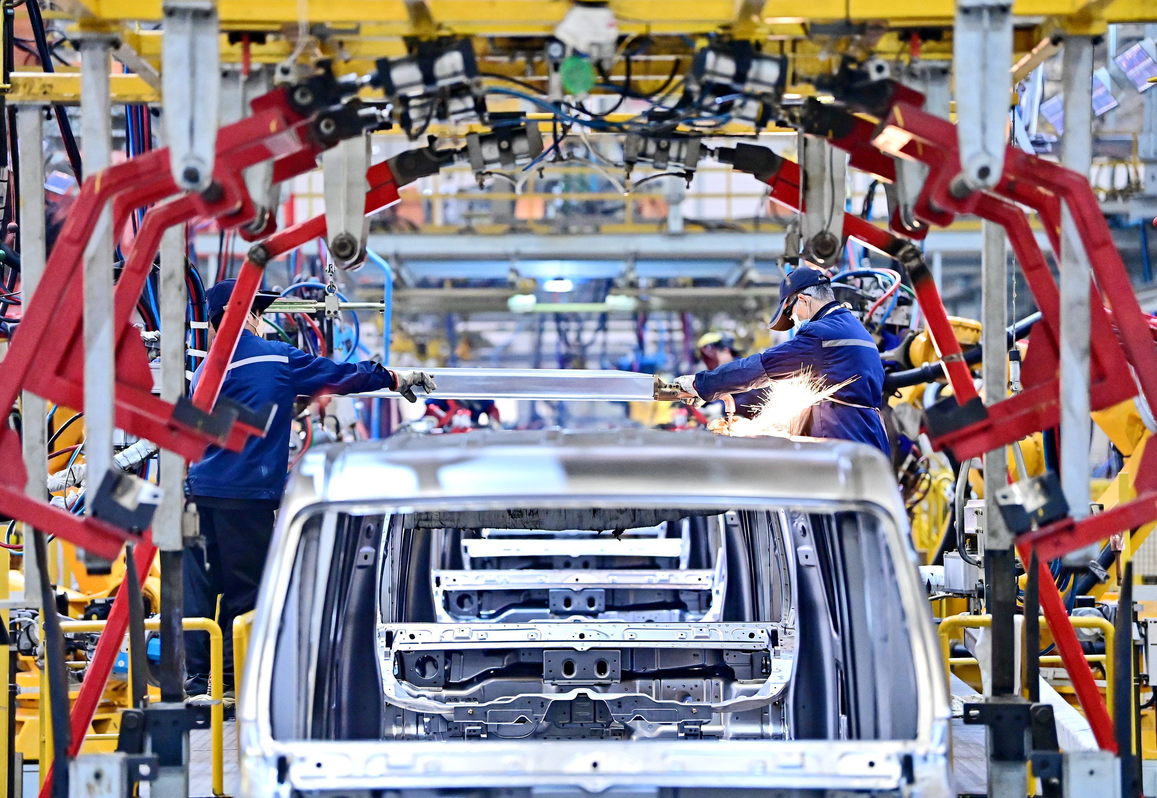 江西省赣州市,工人在冲焊生产线上焊接组装出口南美的新能源电动汽车