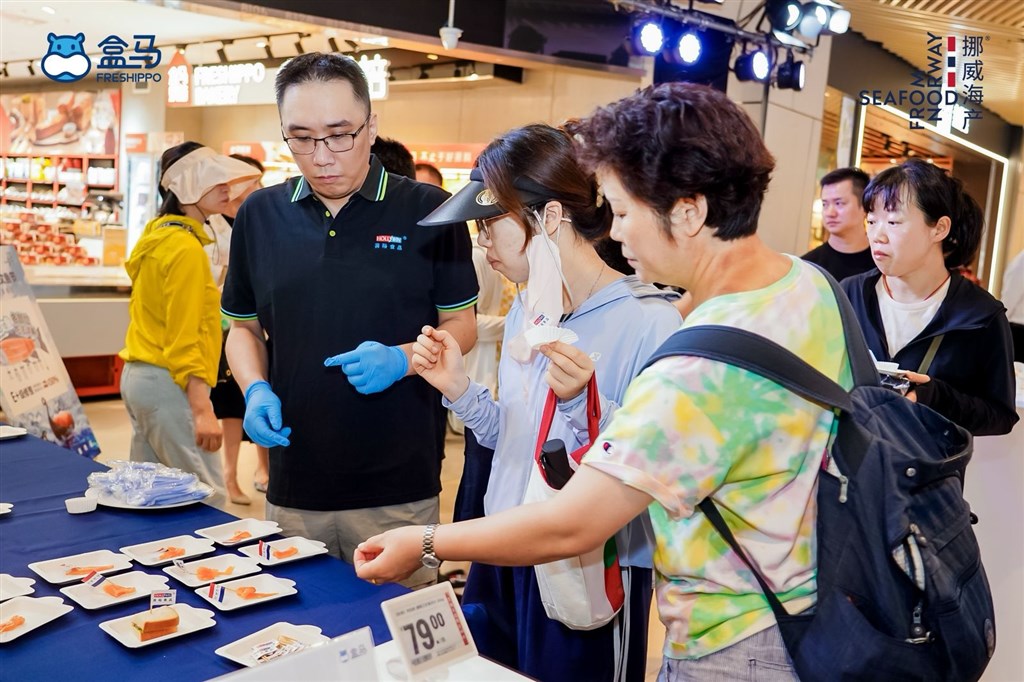 消费者正在挑选品尝新鲜的三文鱼
