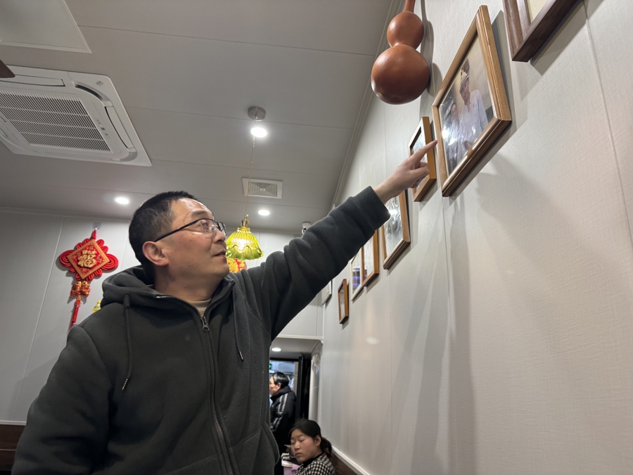 纪文杰向食客们介绍多年前美食节目来店里拍摄的照片。