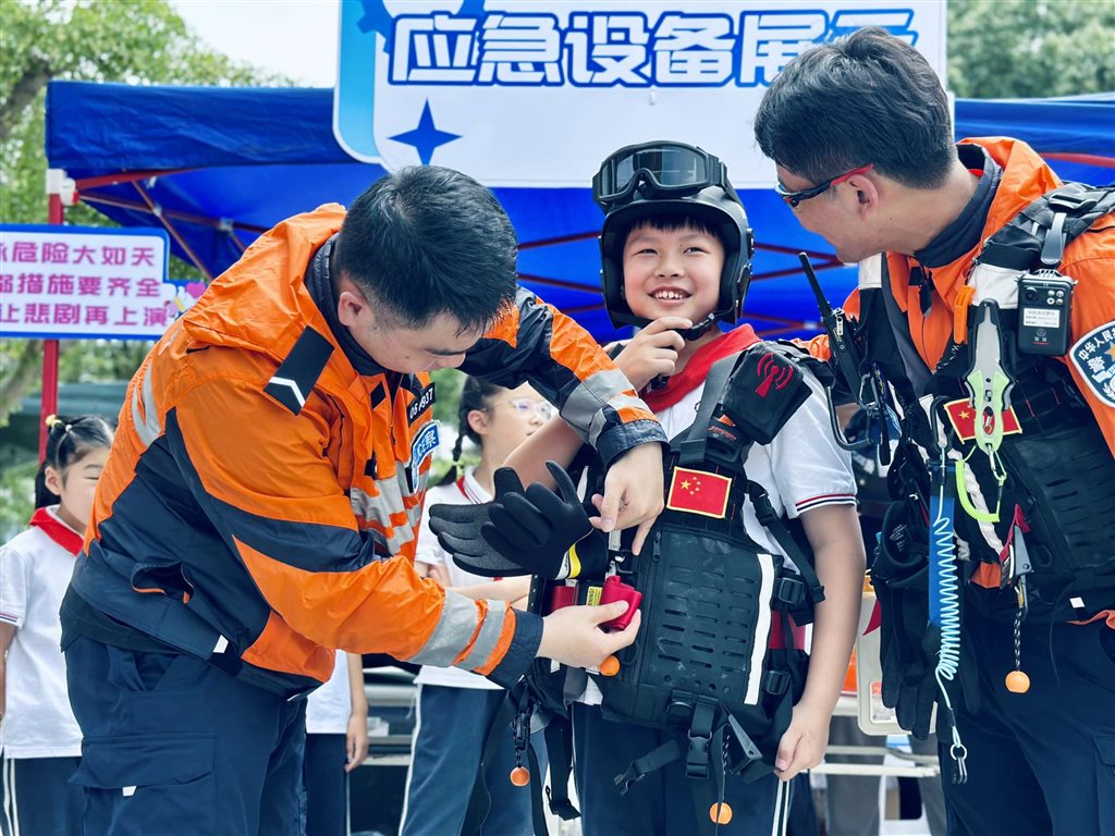 图为边防港航分局水上应急救援队给同学们试穿警用救生装备