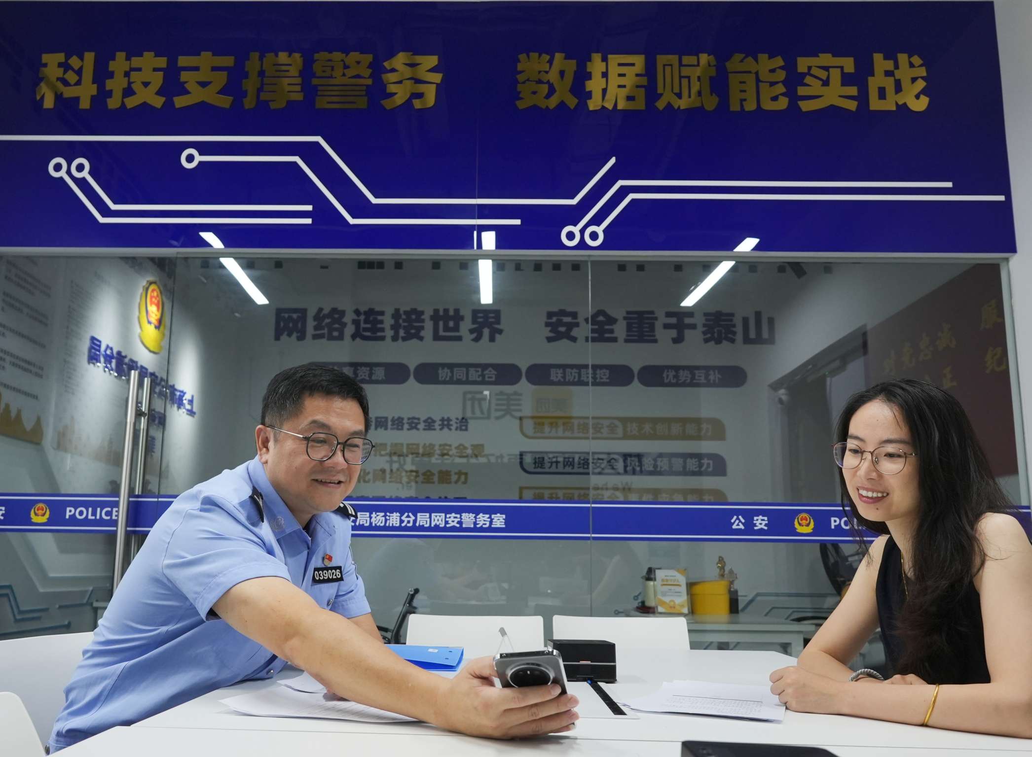 图为杨浦公安分局网安支队民警张哲钦在美团网安警务室为企业负责人解读政策