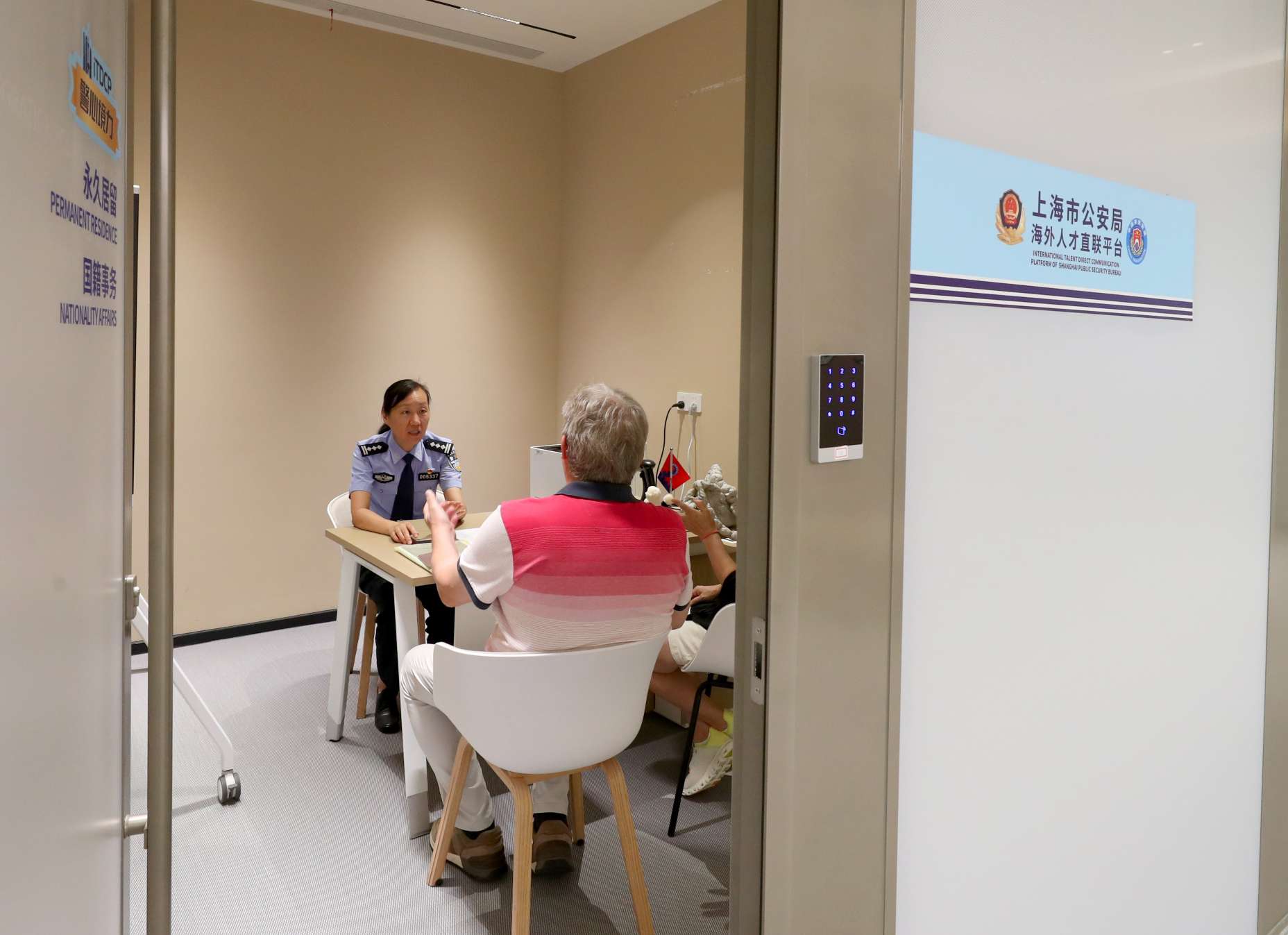 图为直联平台民警向外籍人士介绍永居证办理及便利化应用