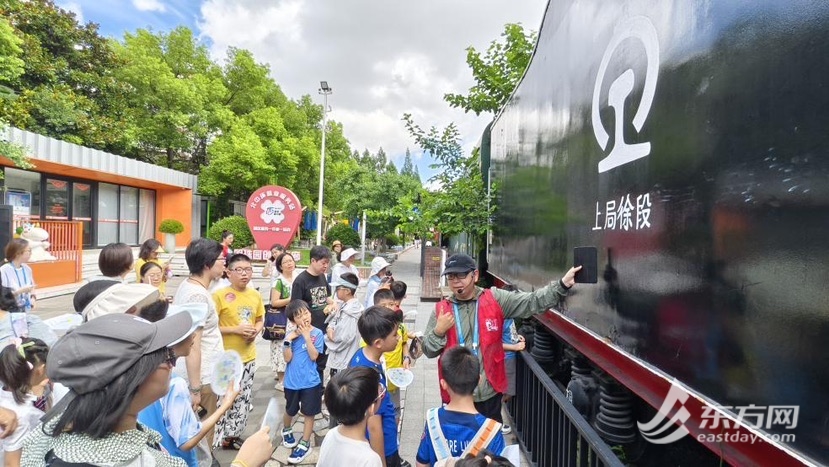 图三 人文行走红队队员们在明珠园火车头广场聆听讲解